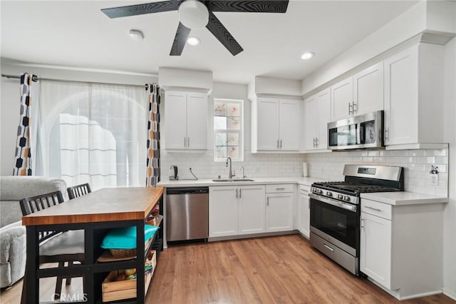 kitchen with sink, light hardwood / wood-style flooring, appliances with stainless steel finishes, white cabinetry, and tasteful backsplash