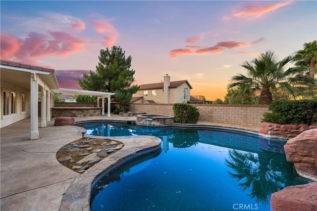 pool at dusk featuring an in ground hot tub and a patio