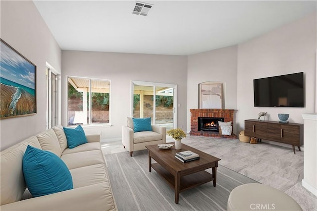 living room featuring lofted ceiling and a brick fireplace