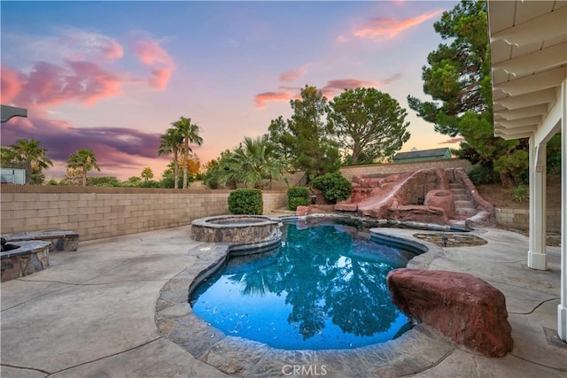 pool at dusk with an in ground hot tub and a patio