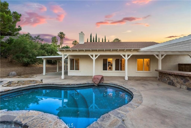 pool at dusk with a patio area