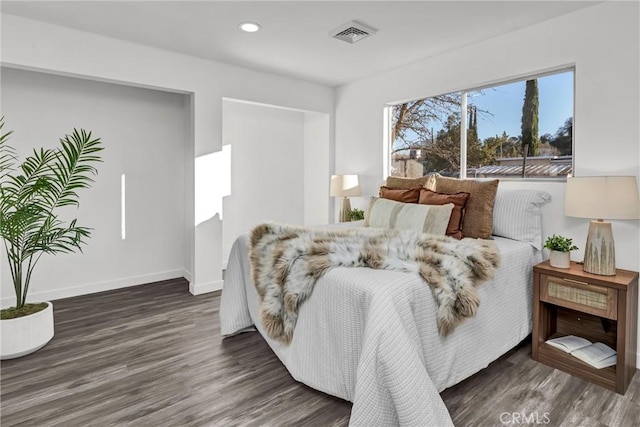 bedroom with multiple windows and dark hardwood / wood-style floors