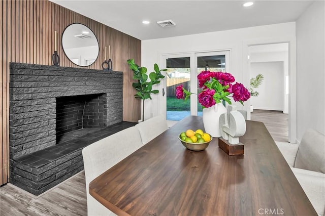 dining space with wood-type flooring and a brick fireplace