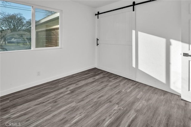 unfurnished room with a barn door and dark wood-type flooring