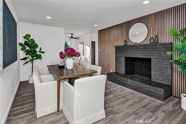 dining space with ceiling fan, a fireplace, and hardwood / wood-style floors