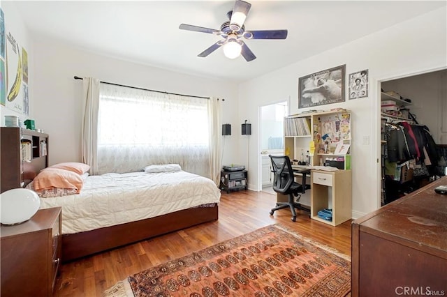 bedroom featuring a spacious closet, wood-type flooring, a closet, and ceiling fan