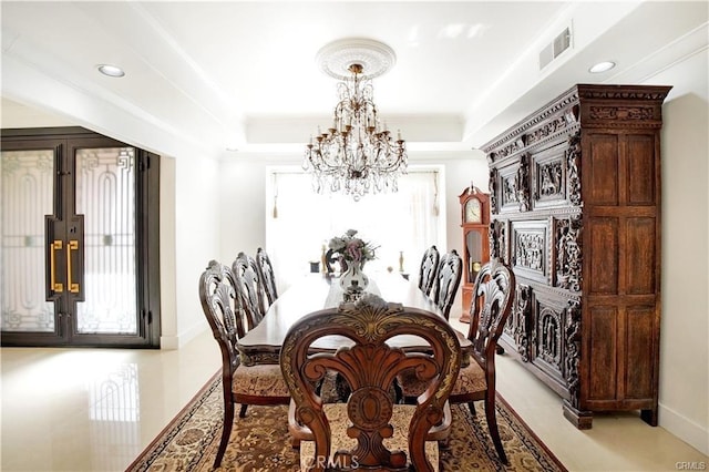 dining room with ornamental molding, an inviting chandelier, and a tray ceiling