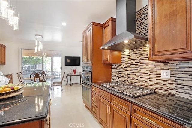 kitchen featuring pendant lighting, dark stone countertops, stainless steel appliances, decorative backsplash, and wall chimney exhaust hood