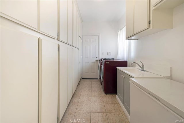 washroom featuring separate washer and dryer, sink, light tile patterned floors, and cabinets