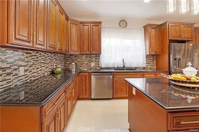 kitchen with sink, light tile patterned floors, dark stone countertops, stainless steel appliances, and decorative backsplash