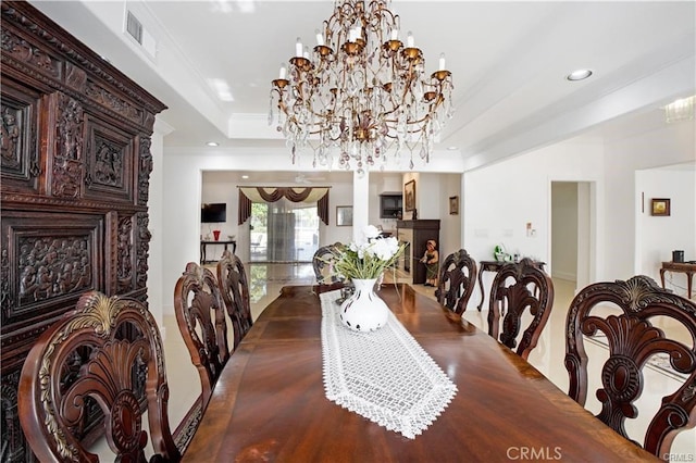 dining area featuring ornamental molding, a raised ceiling, and a chandelier