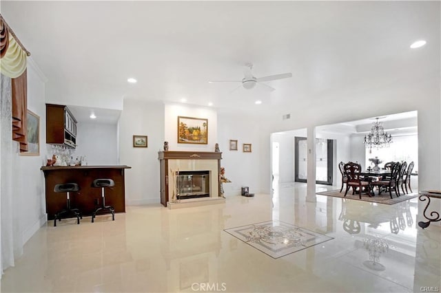 tiled living room with bar area and ceiling fan with notable chandelier