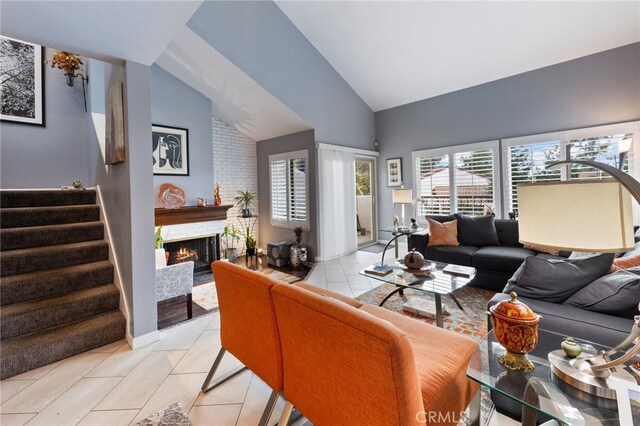 living room with lofted ceiling, a brick fireplace, and light tile patterned flooring