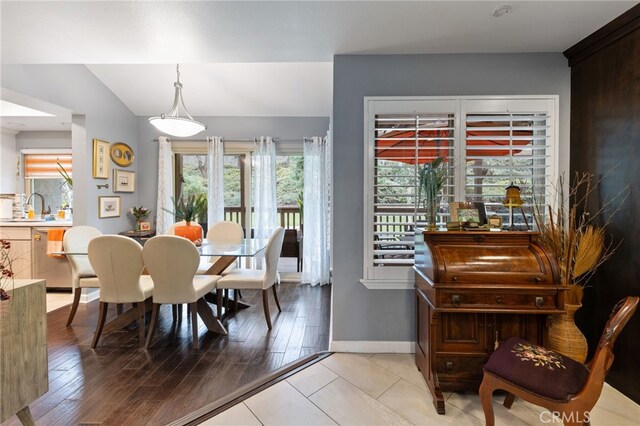 dining space featuring lofted ceiling, sink, and light wood-type flooring