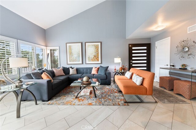 living room featuring high vaulted ceiling and light tile patterned floors