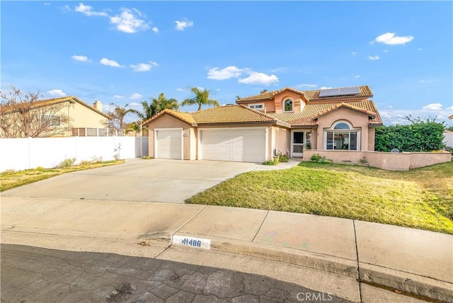 mediterranean / spanish-style home featuring a garage, a front yard, and solar panels