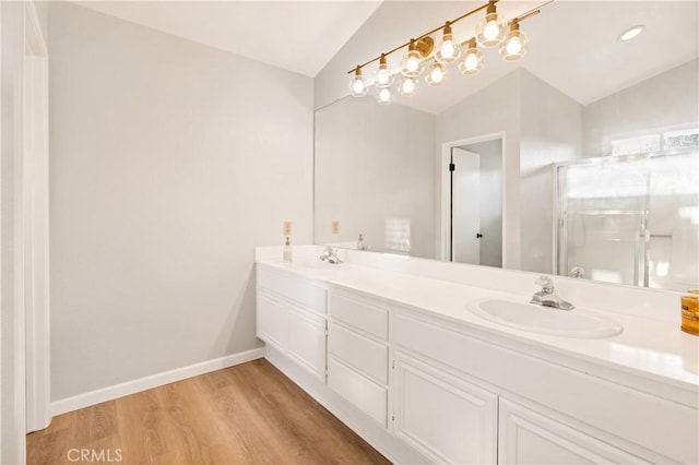 bathroom with hardwood / wood-style flooring, vaulted ceiling, vanity, and a shower with shower door