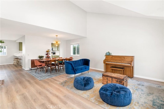 living area with wood-type flooring, high vaulted ceiling, and a chandelier