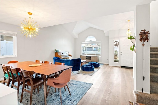 dining room featuring an inviting chandelier, light hardwood / wood-style flooring, and vaulted ceiling