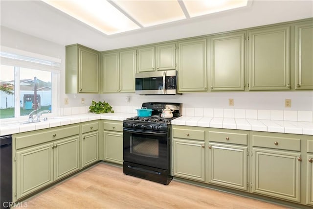 kitchen featuring green cabinetry, sink, and black appliances