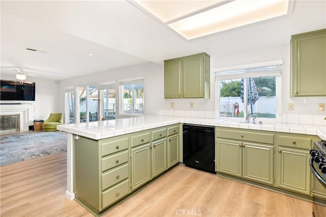 kitchen featuring sink, green cabinets, black appliances, tile countertops, and kitchen peninsula