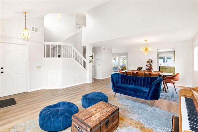 living room with an inviting chandelier, wood-type flooring, and high vaulted ceiling