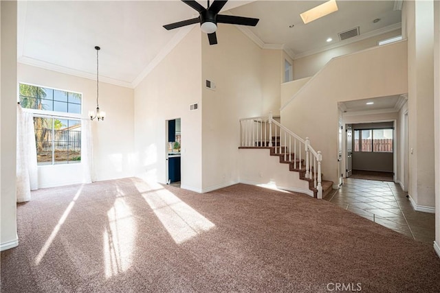 unfurnished living room featuring ornamental molding, a towering ceiling, ceiling fan with notable chandelier, and dark carpet