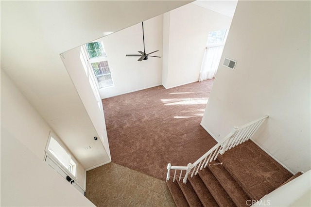 staircase featuring a towering ceiling, carpet floors, and ceiling fan