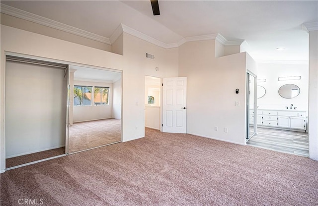 unfurnished bedroom with ceiling fan, ornamental molding, light colored carpet, and a closet