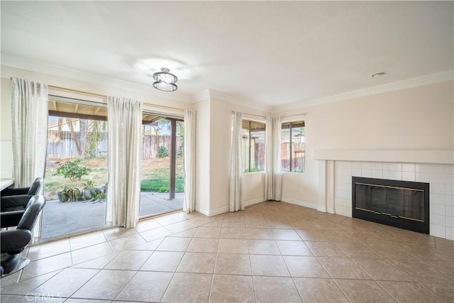 unfurnished living room with a tiled fireplace, crown molding, and light tile patterned flooring