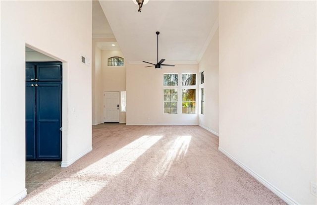 unfurnished living room featuring a high ceiling, crown molding, light colored carpet, and ceiling fan