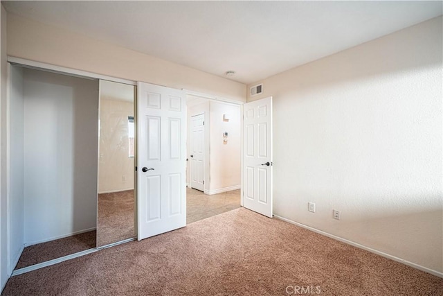 unfurnished bedroom featuring light carpet and a closet