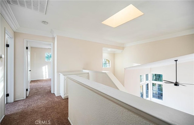 hallway with crown molding, dark carpet, and a skylight