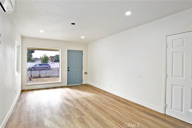 spare room featuring a wall mounted AC and light wood-type flooring