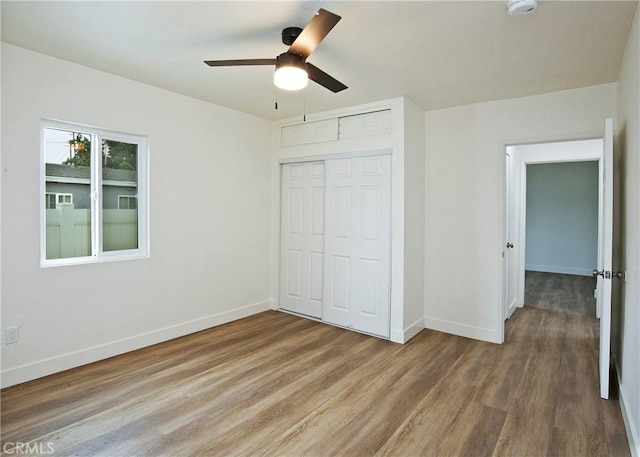 unfurnished bedroom featuring ceiling fan, wood-type flooring, and a closet