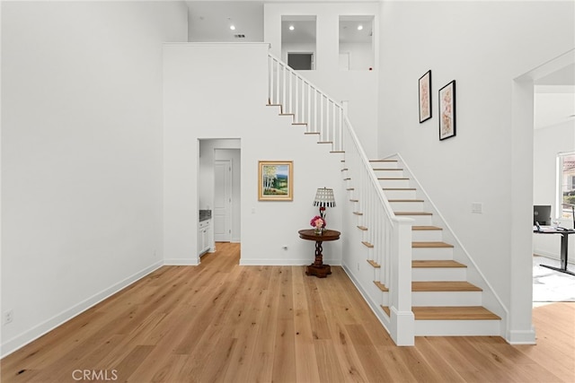 stairs featuring baseboards, a high ceiling, and wood finished floors