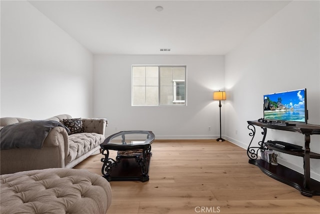 living room with light wood-type flooring, visible vents, and baseboards