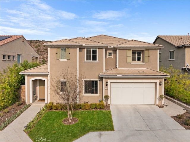 view of front of house with stucco siding, an attached garage, a front yard, driveway, and a tiled roof