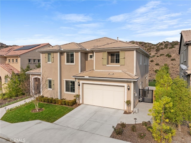 traditional-style house with a tile roof, stucco siding, concrete driveway, fence, and a garage