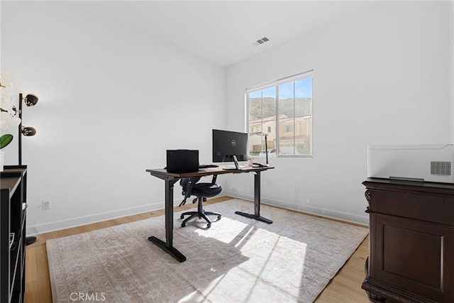 office area featuring light wood finished floors, baseboards, and visible vents