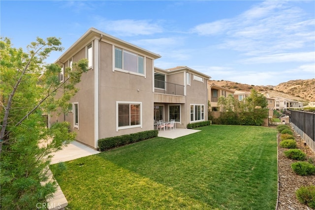 rear view of property featuring a patio area, a fenced backyard, a yard, and stucco siding