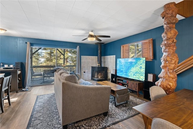 living room featuring ceiling fan, a wood stove, and light wood-type flooring