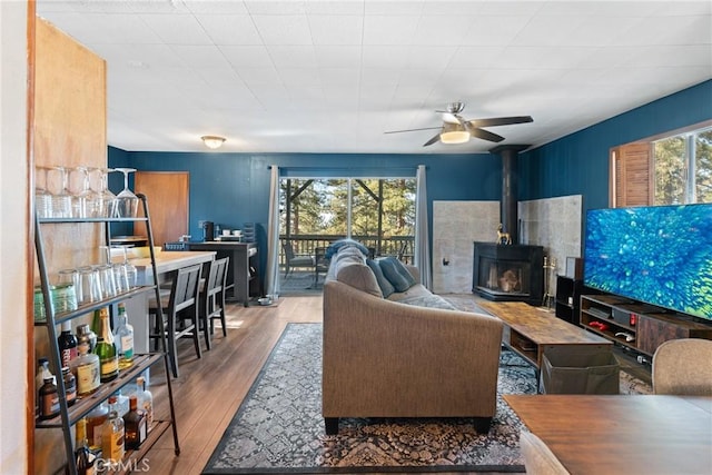 living room featuring hardwood / wood-style flooring, ceiling fan, and a wood stove