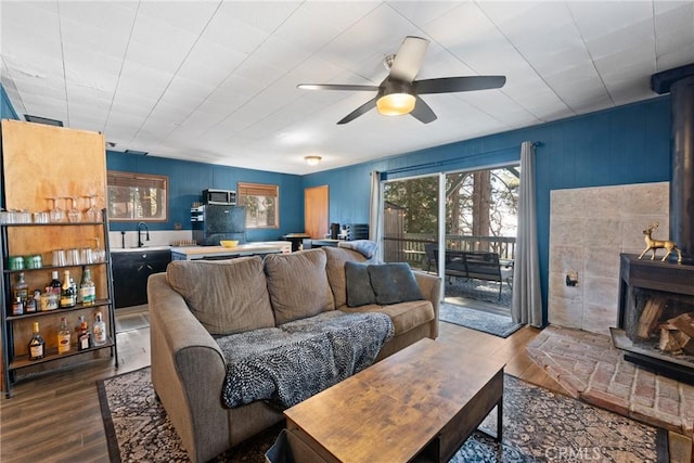 living room featuring ceiling fan, hardwood / wood-style floors, and a wood stove