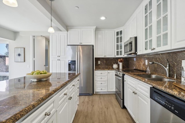 kitchen featuring pendant lighting, appliances with stainless steel finishes, dark stone counters, and white cabinets