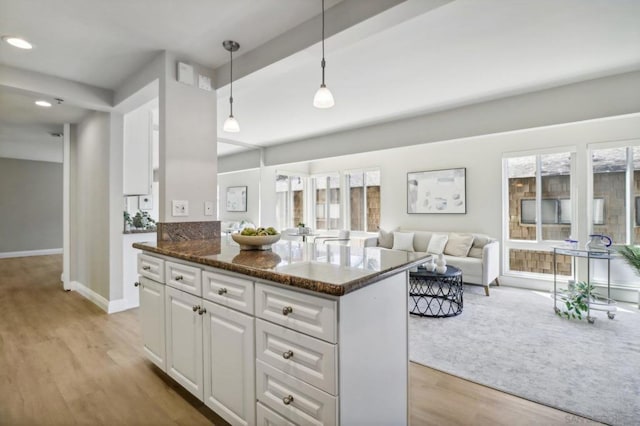 kitchen with dark stone countertops, pendant lighting, white cabinets, and light wood-type flooring