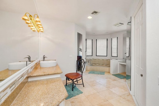 bathroom featuring tile patterned floors, vanity, and tiled bath