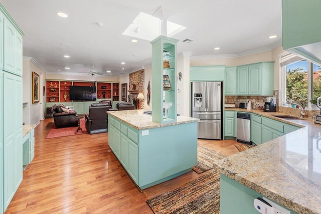 kitchen featuring sink, a center island, light wood-type flooring, stainless steel fridge, and light stone countertops