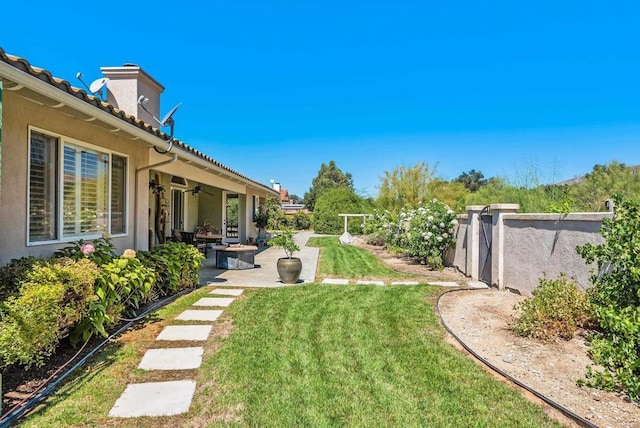 view of yard with ceiling fan and a patio