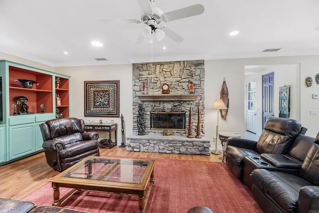 living room featuring hardwood / wood-style flooring, crown molding, a stone fireplace, and ceiling fan